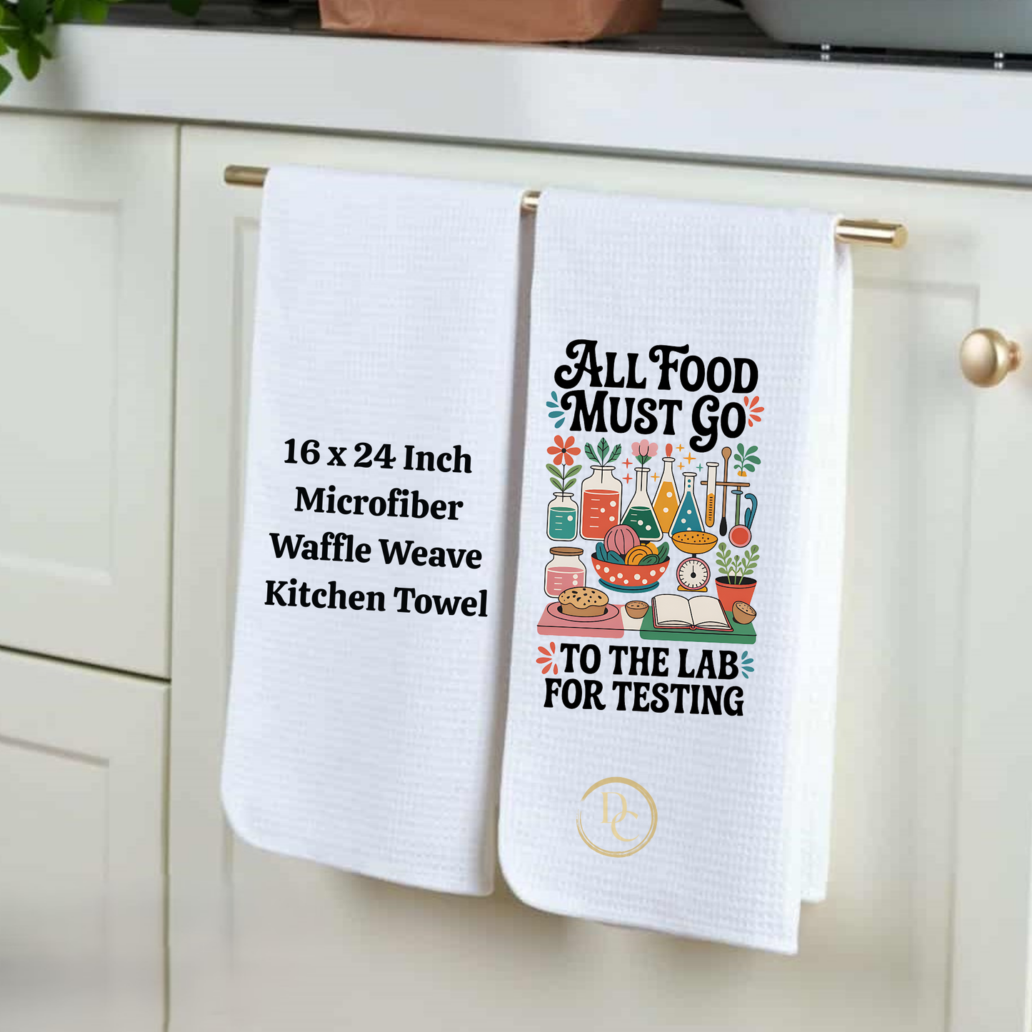 White kitchen towel with humorous design and text hanging on a cabinet handle.