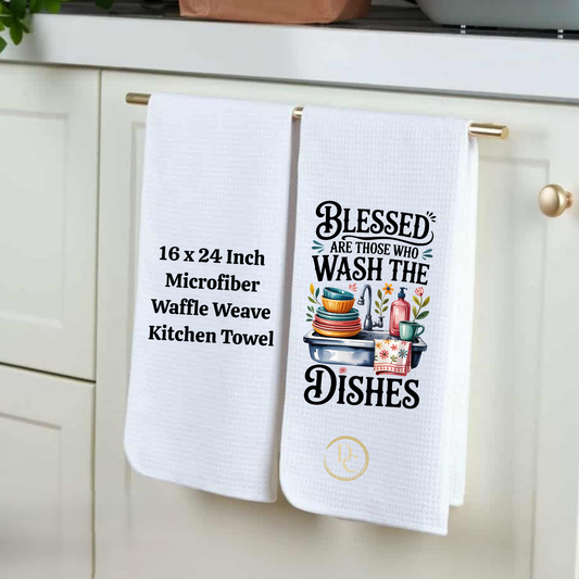 Two white kitchen towels hanging on a cabinet handle, one with text and the other with a graphic design.