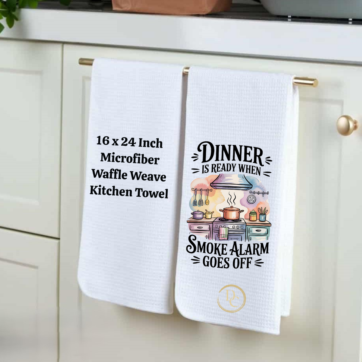 Two kitchen towels hanging on a cabinet, one with text and the other with a graphic design.