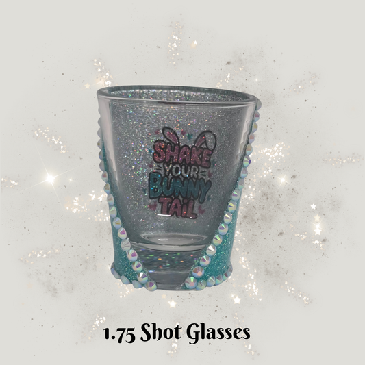 Decorative shot glass with glittery rim and text on a sparkling background